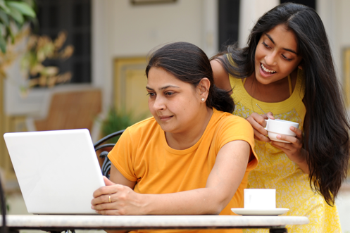 Two women in India using a computer to enter Online Portal Form C checkout dates