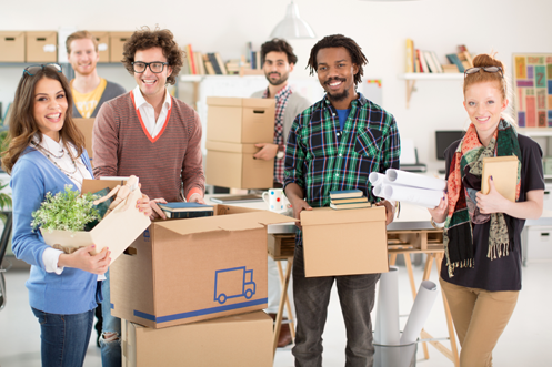 Two female and four male employees packing up boxes for a corporate relocation after confirming their business relocation budget
