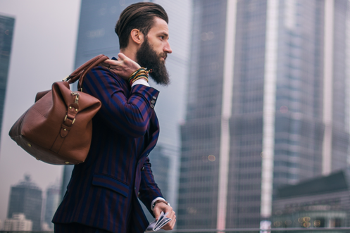 Business man with beard walking through Shanghai, carrying a leather bag, in country legally with China Working Visas and Work Permits