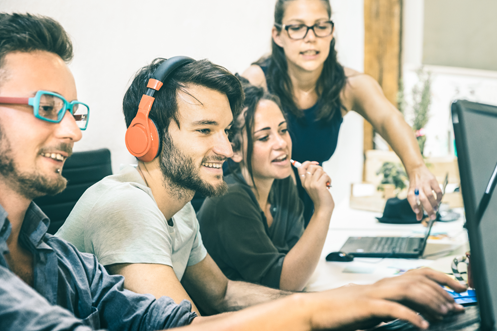 Two men and two women employees at work, discussing Human Resources Innovation and Talent Management as they look at a computer screen to review relocation technology