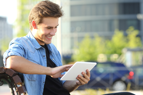 Handsome cleanshaven man with brown hair, looking at a tablet, watching a video series
