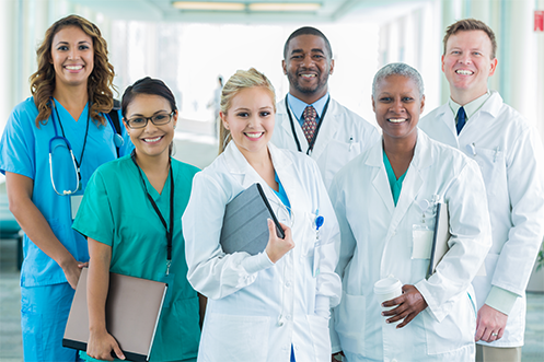 Four women and two men in healthcare uniforms, diverse races, diverse ages, diverse looks, smiling, standing together, happy because they have benefitted from healthcare industry relocation trends