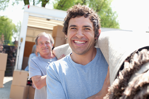 Smiling handsome man carrying roll of carpet, wearing blue t-shirt, grateful for his Lump Sum Self-Service