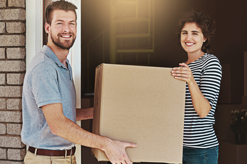 Smiling man with brown hair and beard, holding a cardboard box with a woman, he is glad for the Benefits of Pre-Decision Services which helped him determine to take a relocation assignment