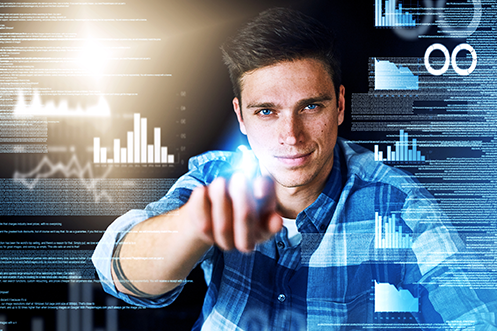 Young man smiling, wearing a blue plaid shirt, with brown hair and blue eyes, pointing forward at data on a computer screen, performing a security assessment
