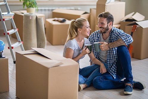 Blonde woman sitting, smiling, holding coffee cup, man with brown hair and beard, sitting, smiling, holding coffee cup, both happy with their managed cap relocation programs