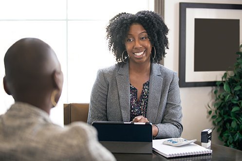Women with dark curly hair, smiling, wearing a jacket, facing another person while discussing which states are enacting workarounds