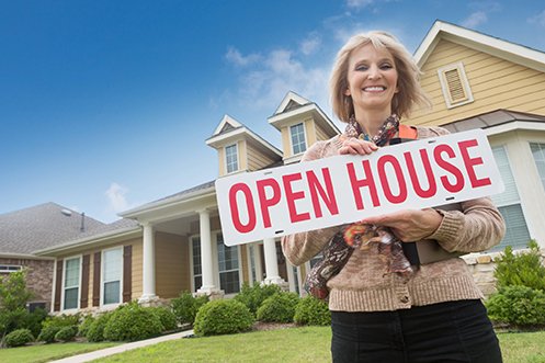 Female real estate agent holding open house sign in the middle of creating virtual agent services
