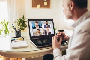 Two male and two female Relocation Management Company representatives presenting their proposal by video to a male Human Resource Professional who hopes to gain expedited bidding benefits