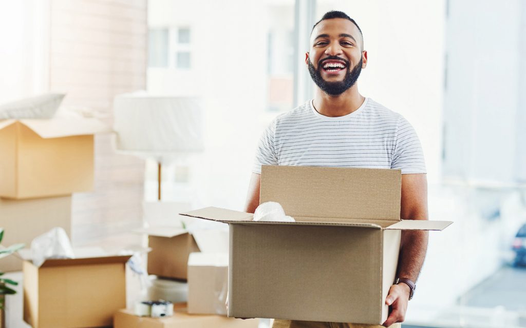 man smiling while moving boxes into his new home