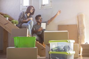 young couple unpacking moving boxes in new apartment