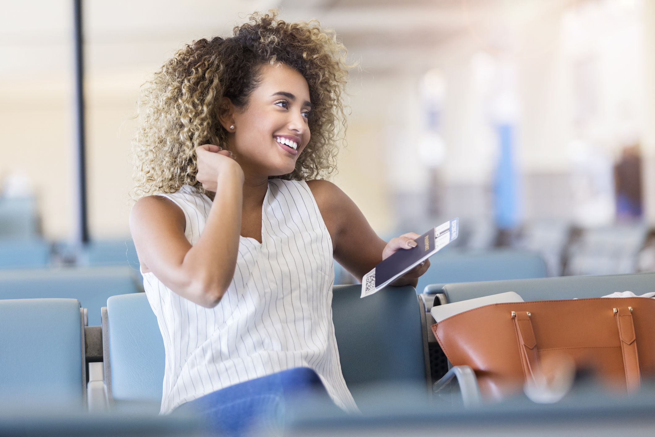 good looking woman waiting in airport, holding passport