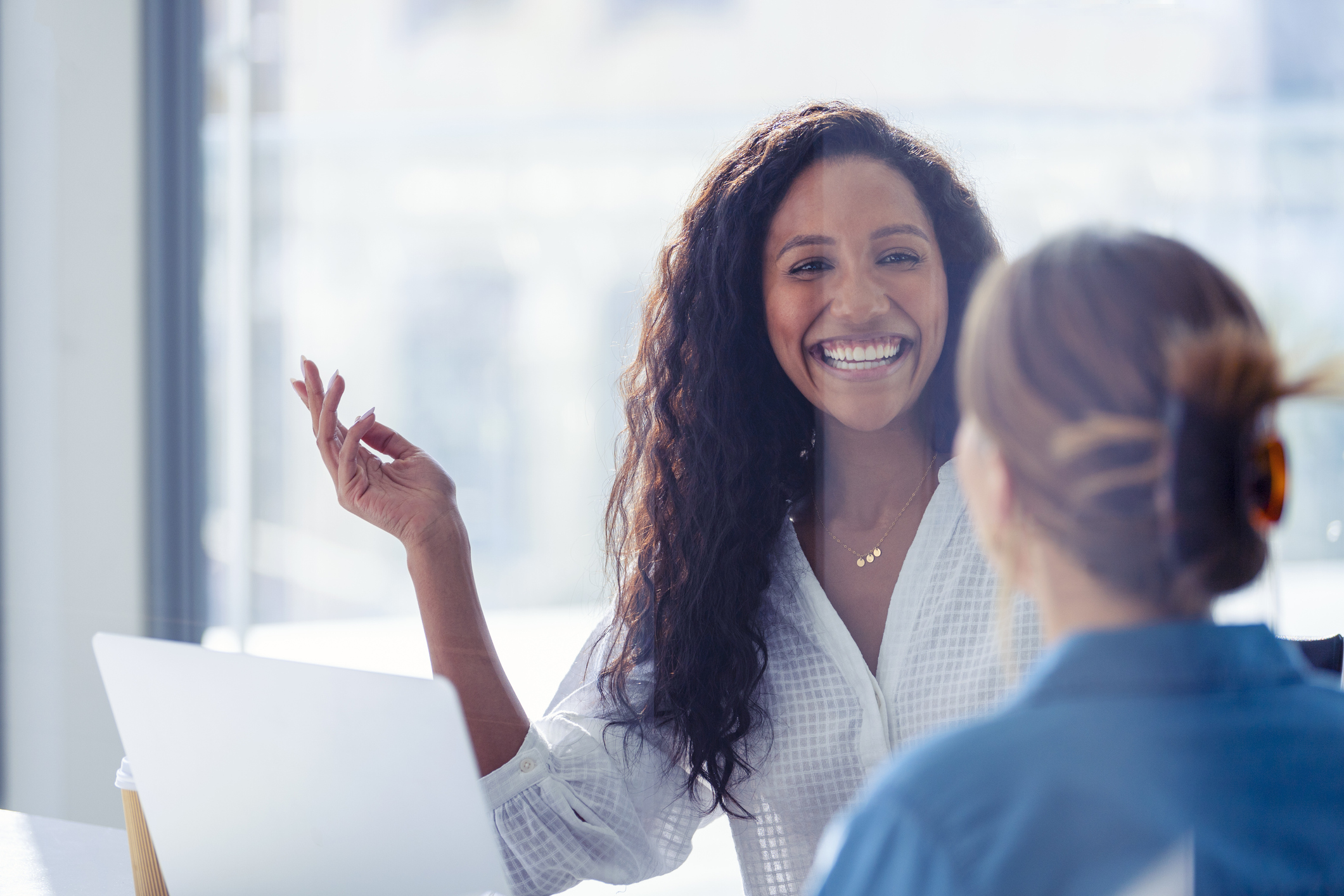 young female employee smiling while speaking with coworker