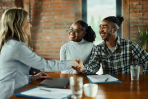 young African-American couple meets with female real estate agent.