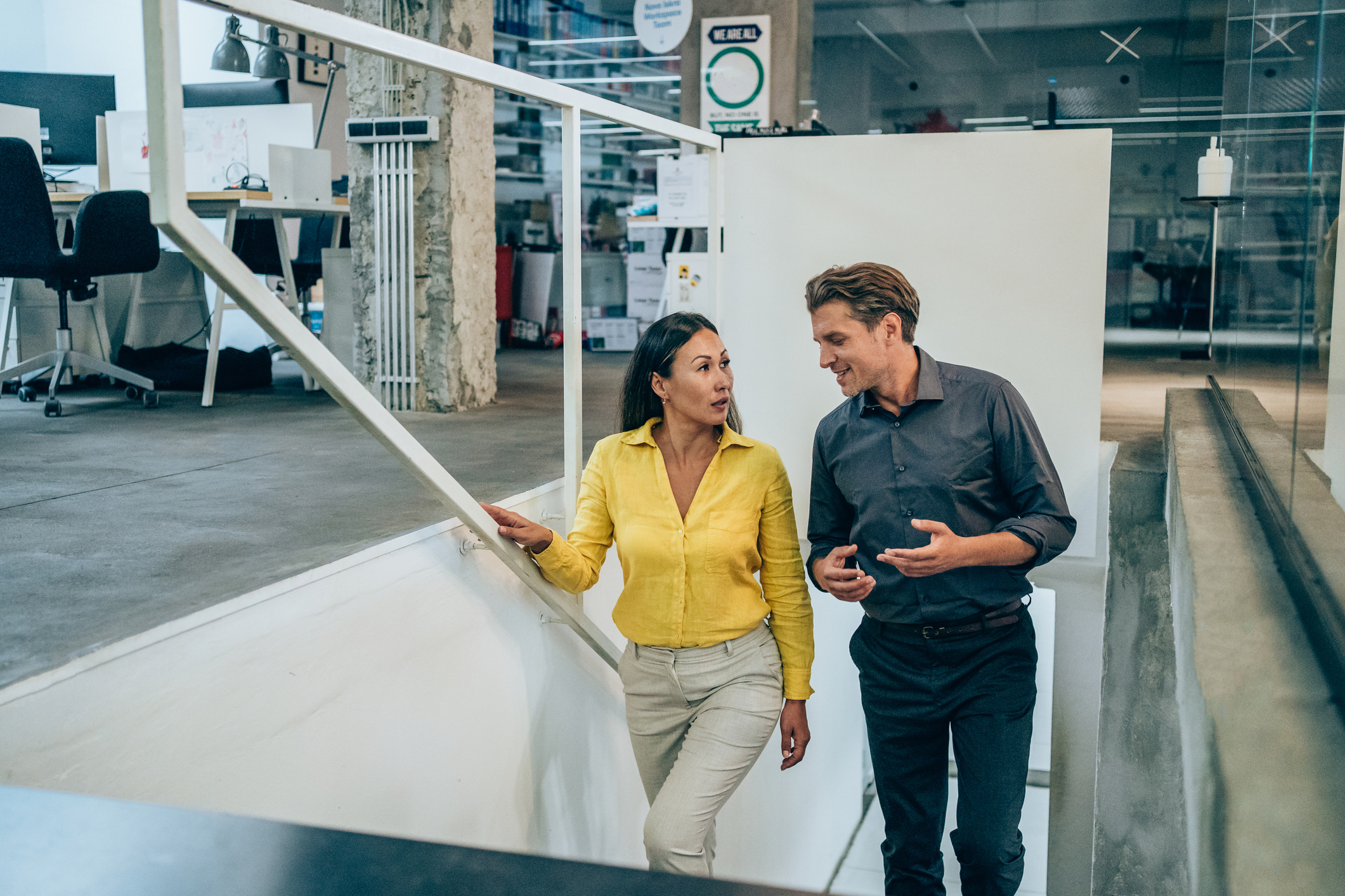 two young business people walking up stairs while talking about work