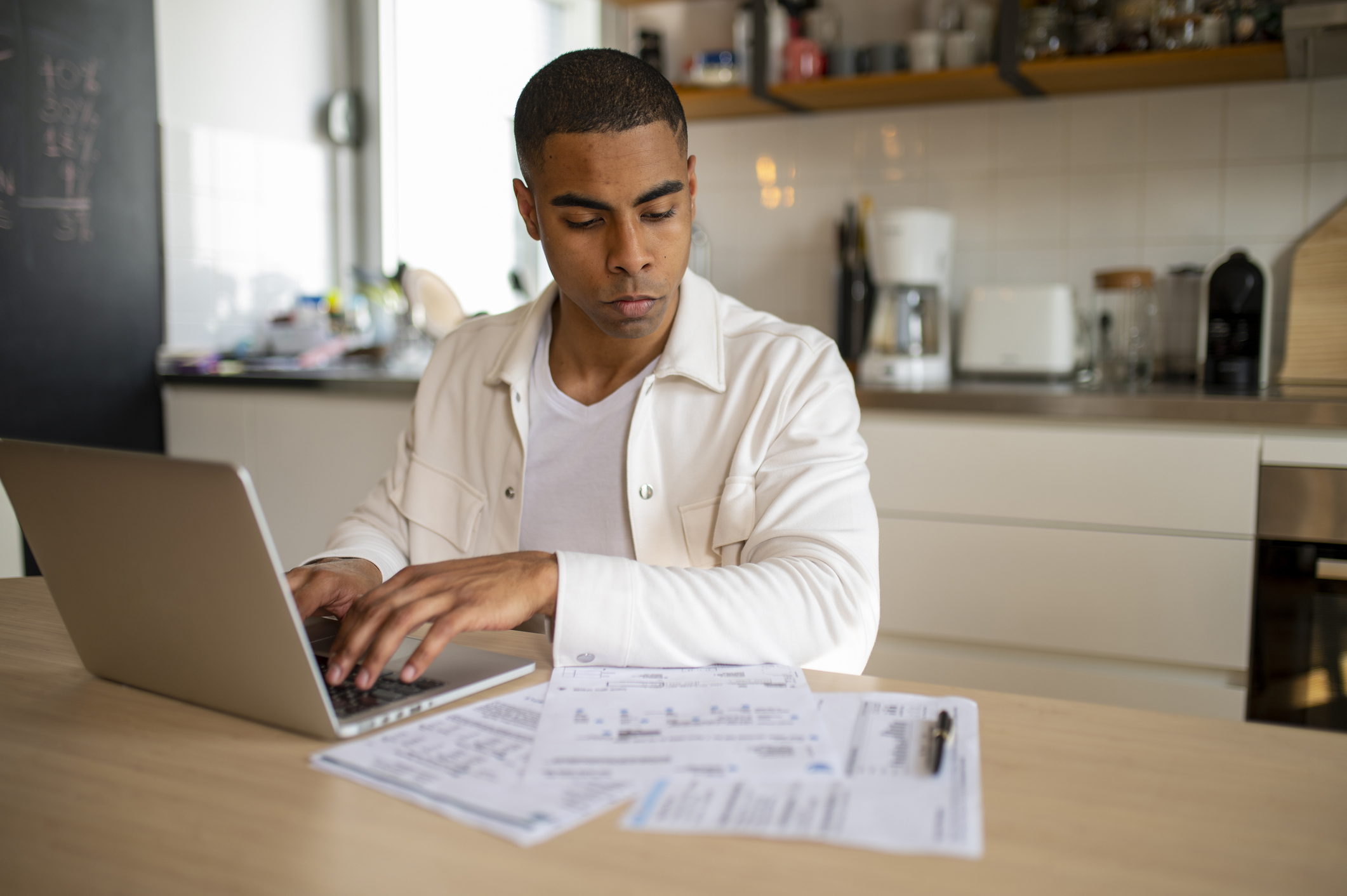 Man in his late 20s filing his taxes at kitchen table