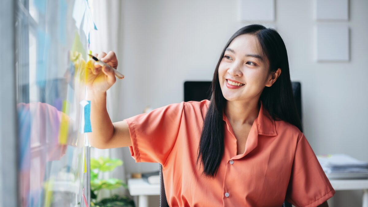young asian woman in business casual clothes using relocation checklist on whiteboard