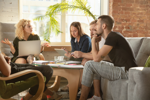 group of younger coworkers working together in office happily