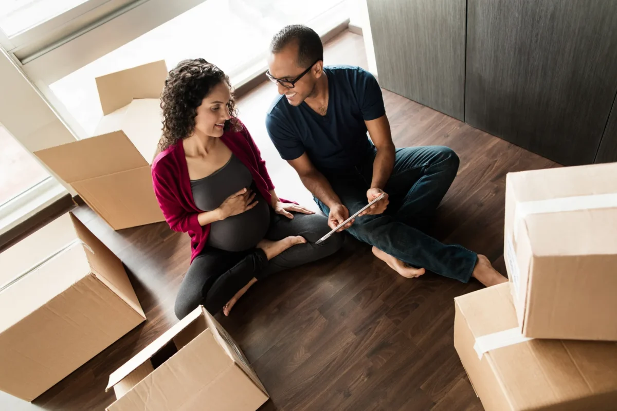 Pregnant couple shopping online while packing their things.