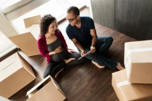Pregnant couple shopping online while packing their things.