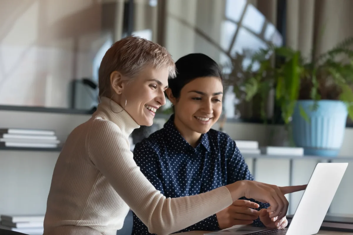 two women working together on laptop, learning a new language