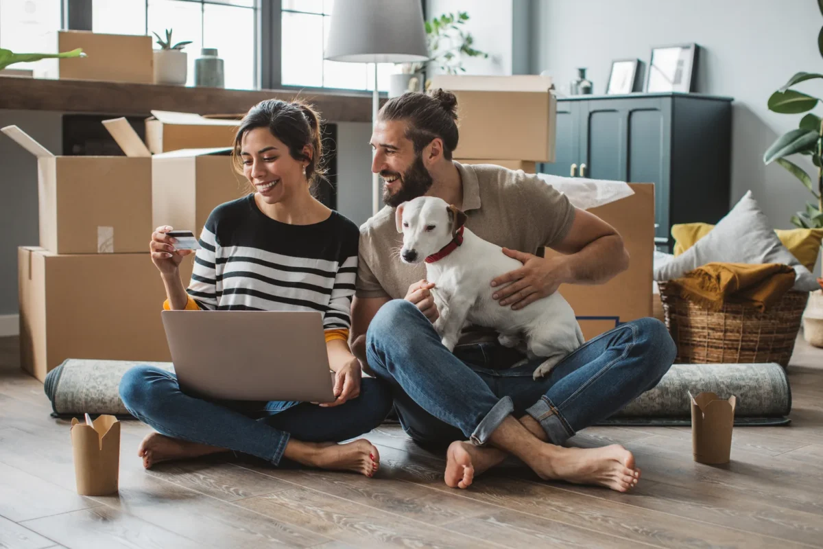 Young couple moving in new house. They are happy and using laptop.