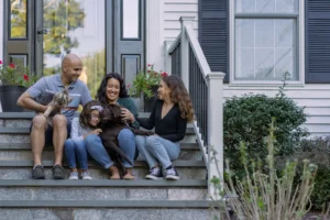 happy family sitting on front steps of home petting their dogs