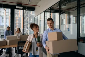 Coworkers helping each other getting moving boxes ready