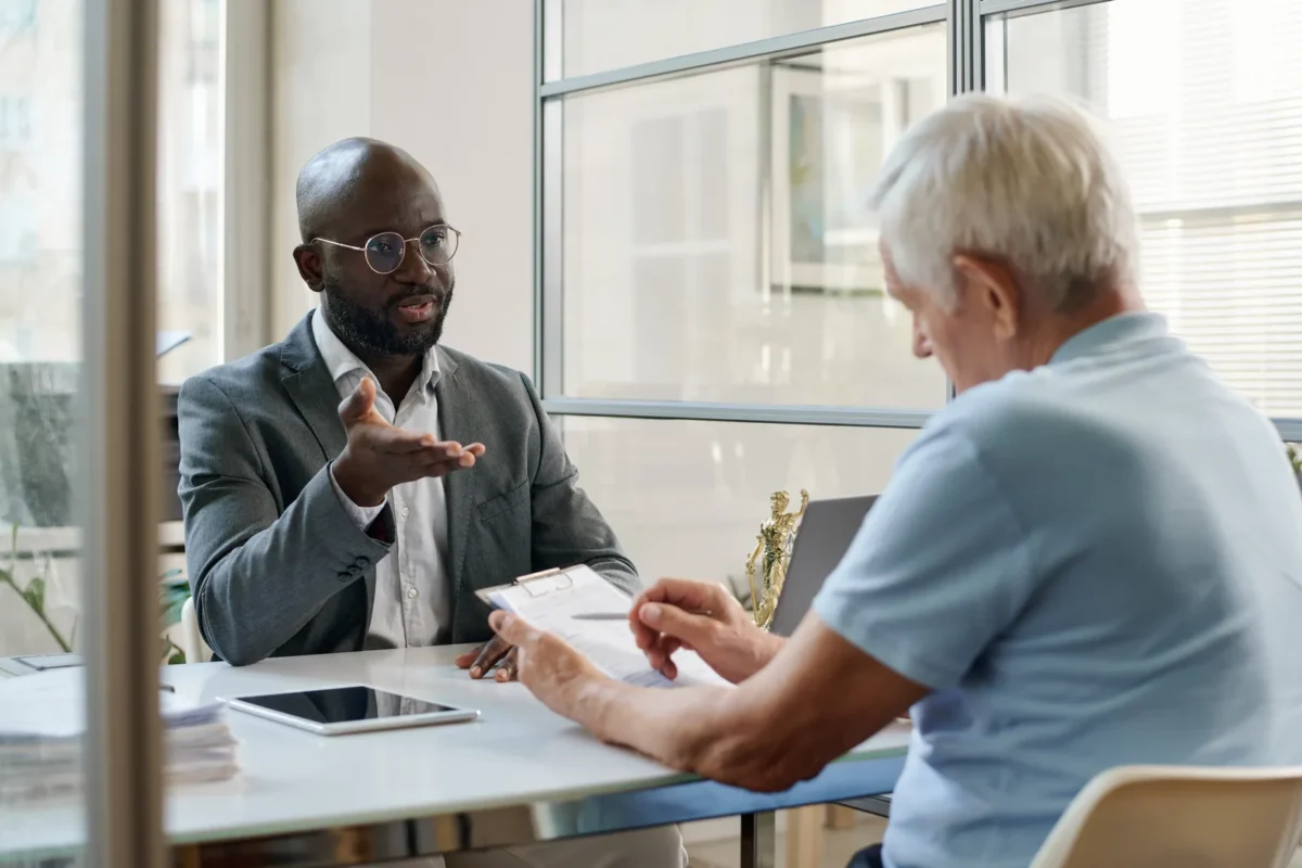 Visa and immigration specialist going over paperwork with elderly man.