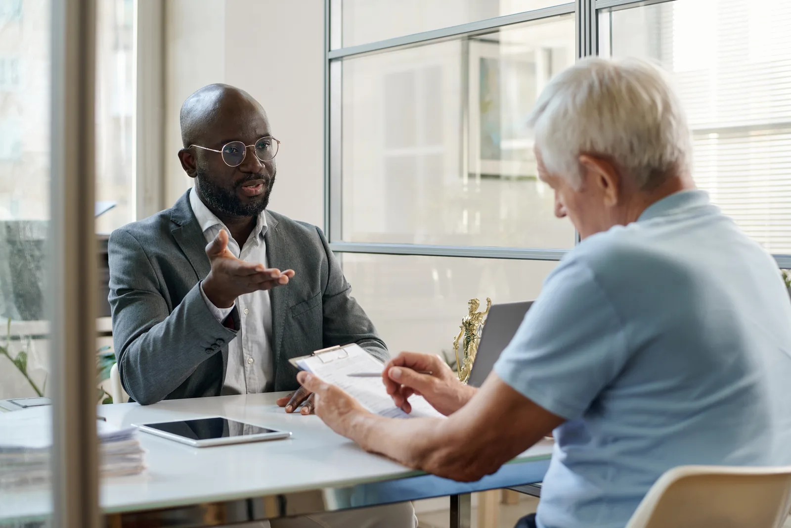 Visa and immigration specialist going over paperwork with elderly man.